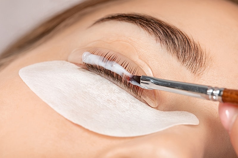 Applying eyelash treatment with a brush.