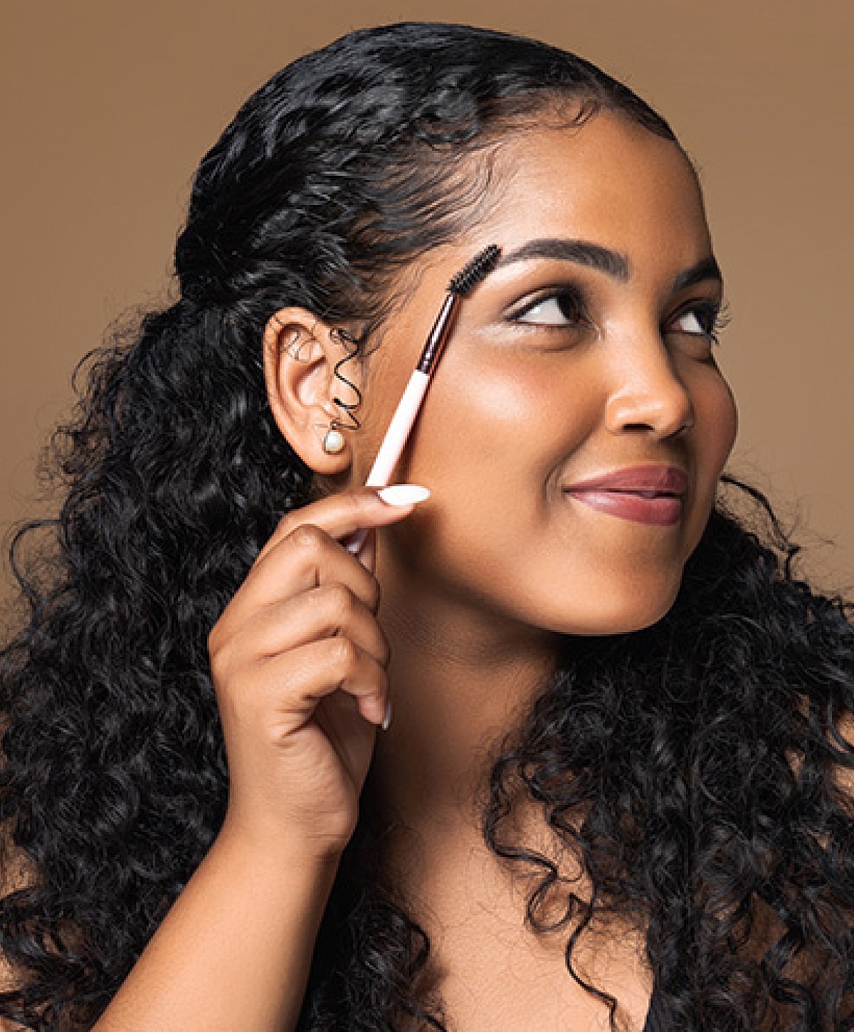 Woman styling her eyebrows with makeup tool