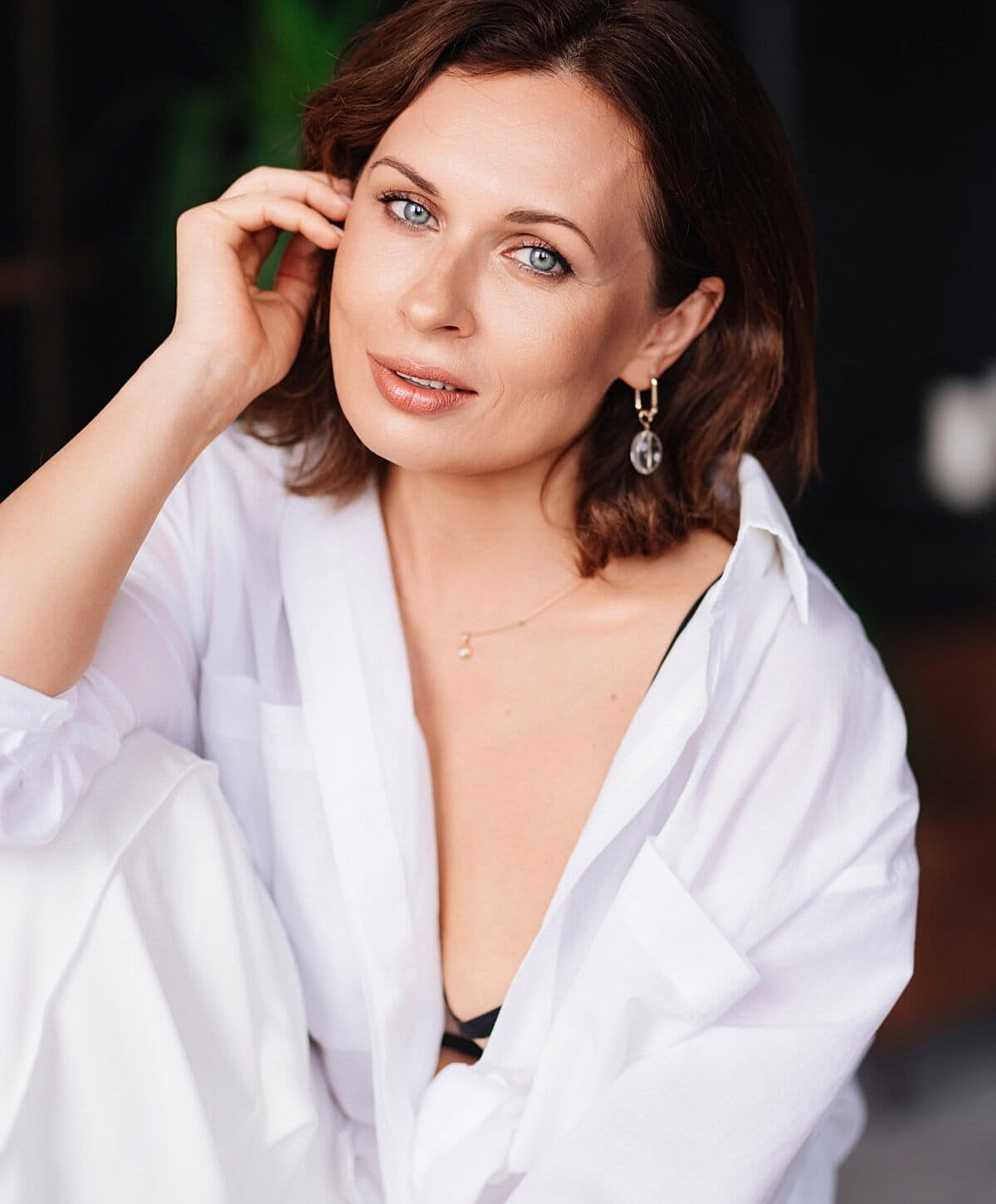 Woman in white shirt, relaxed, smiling softly.