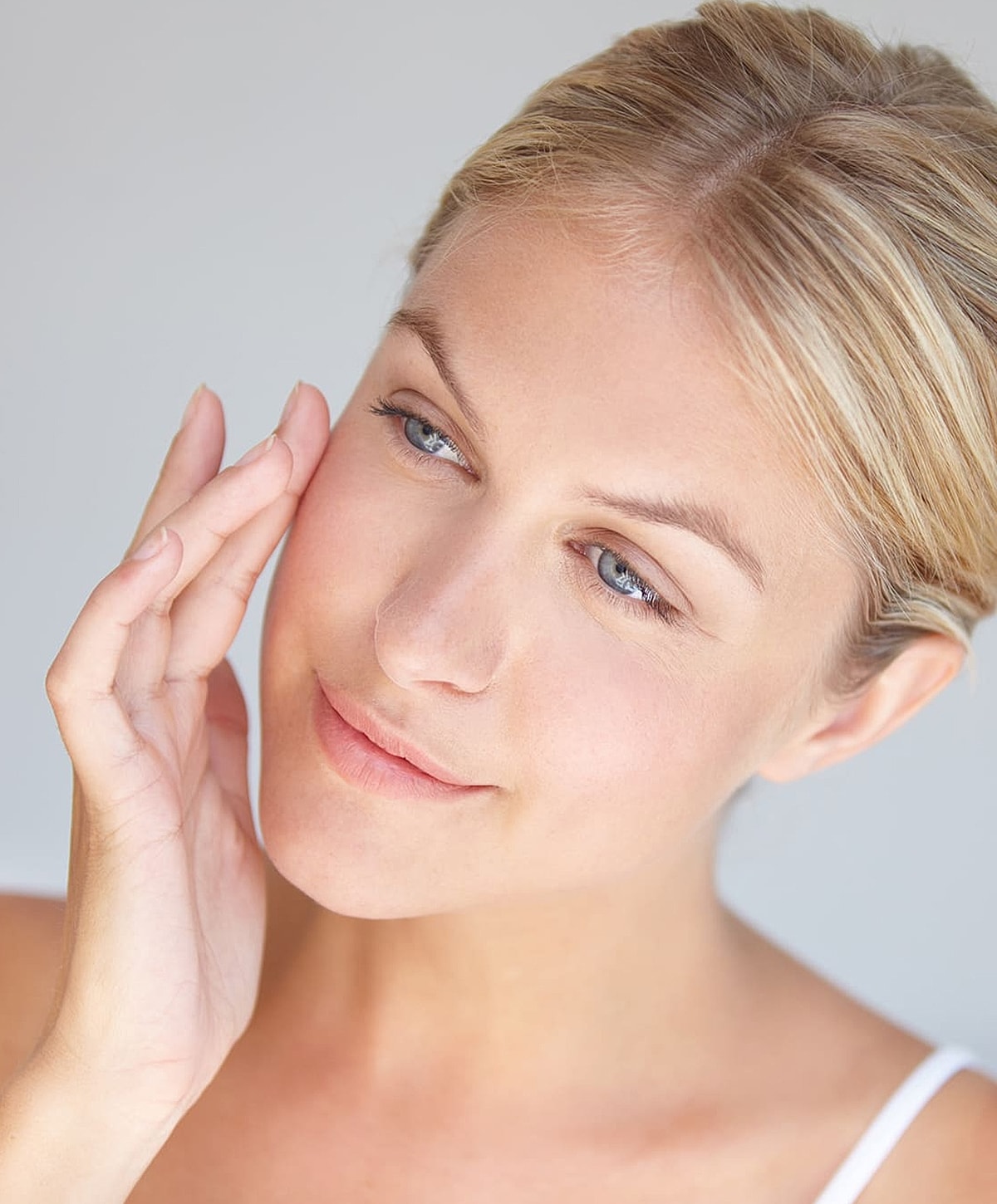 Woman applying skincare on her face.