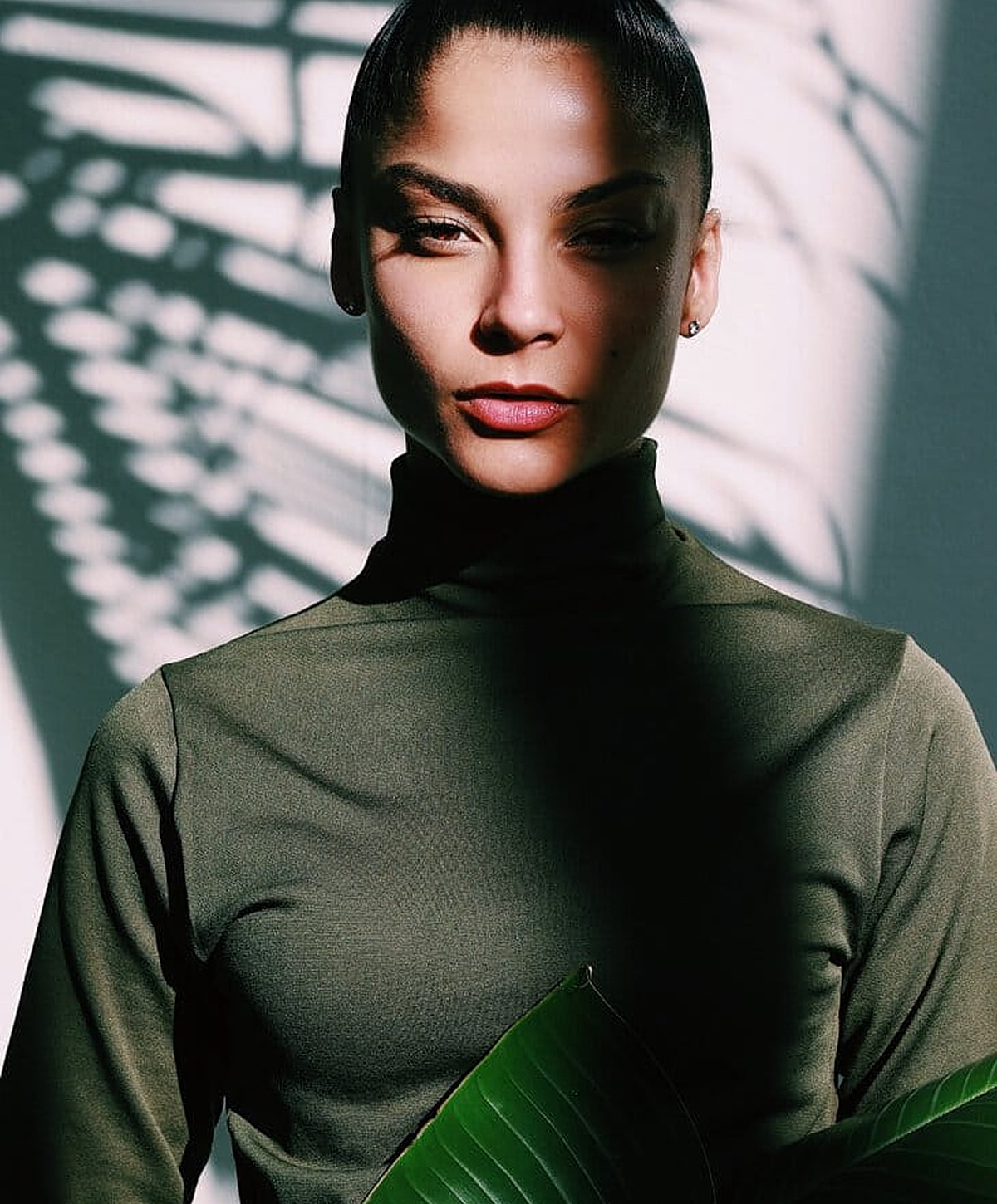 Woman in green top with dramatic shadows.