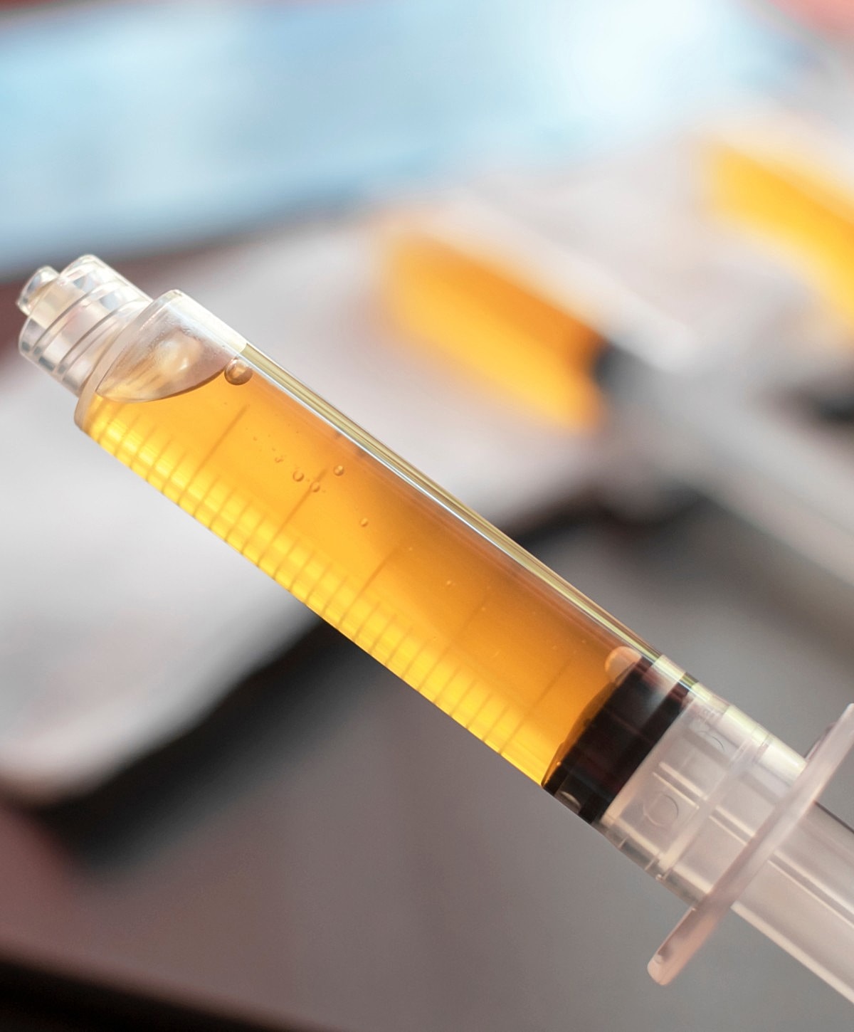 Syringe containing amber liquid on a surface.