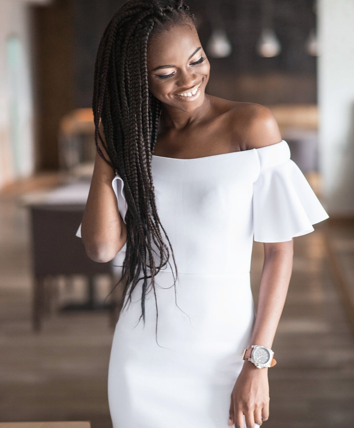 Woman in white dress with braided hair, smiling.