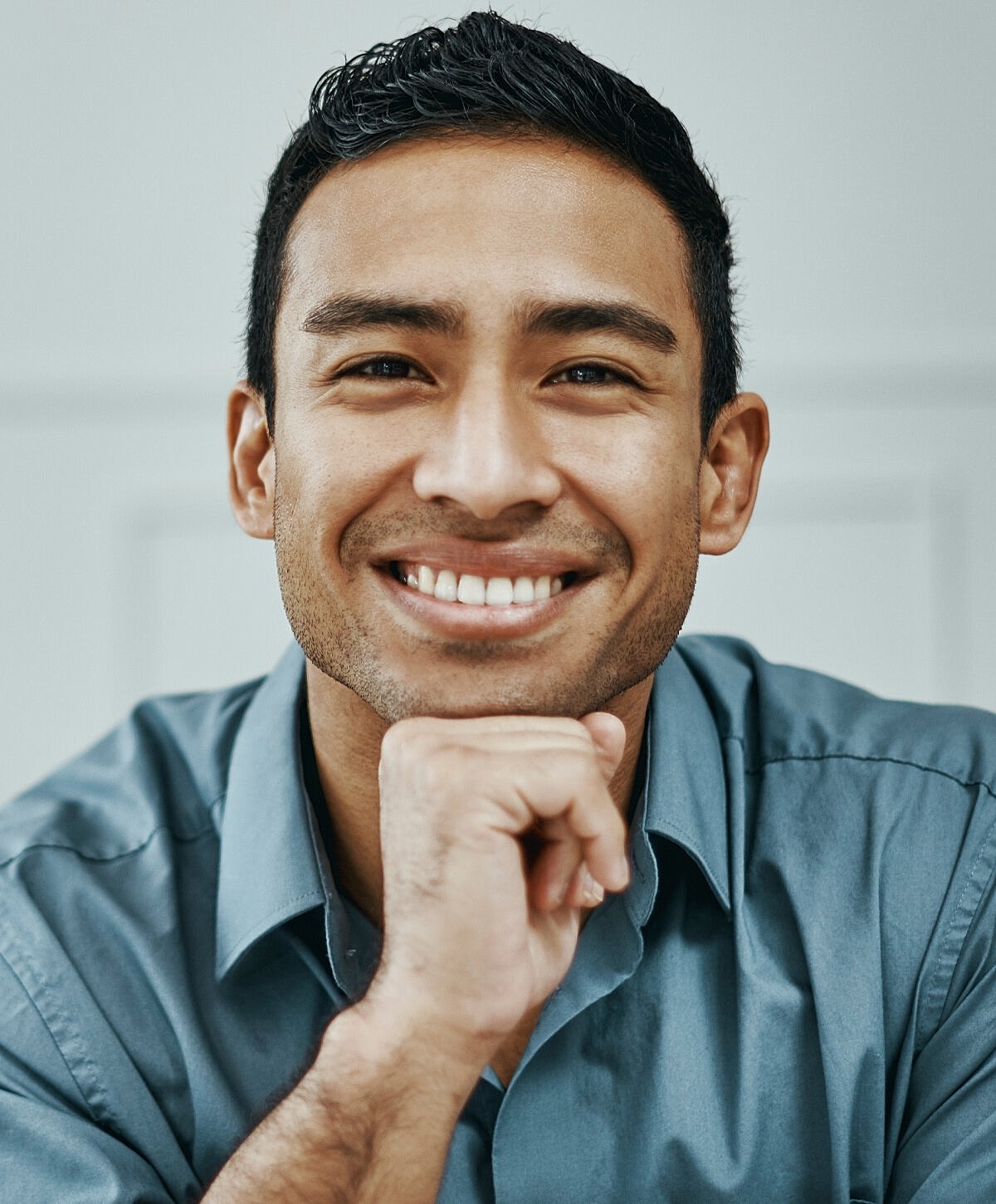 Smiling man in a blue shirt, thoughtful pose.