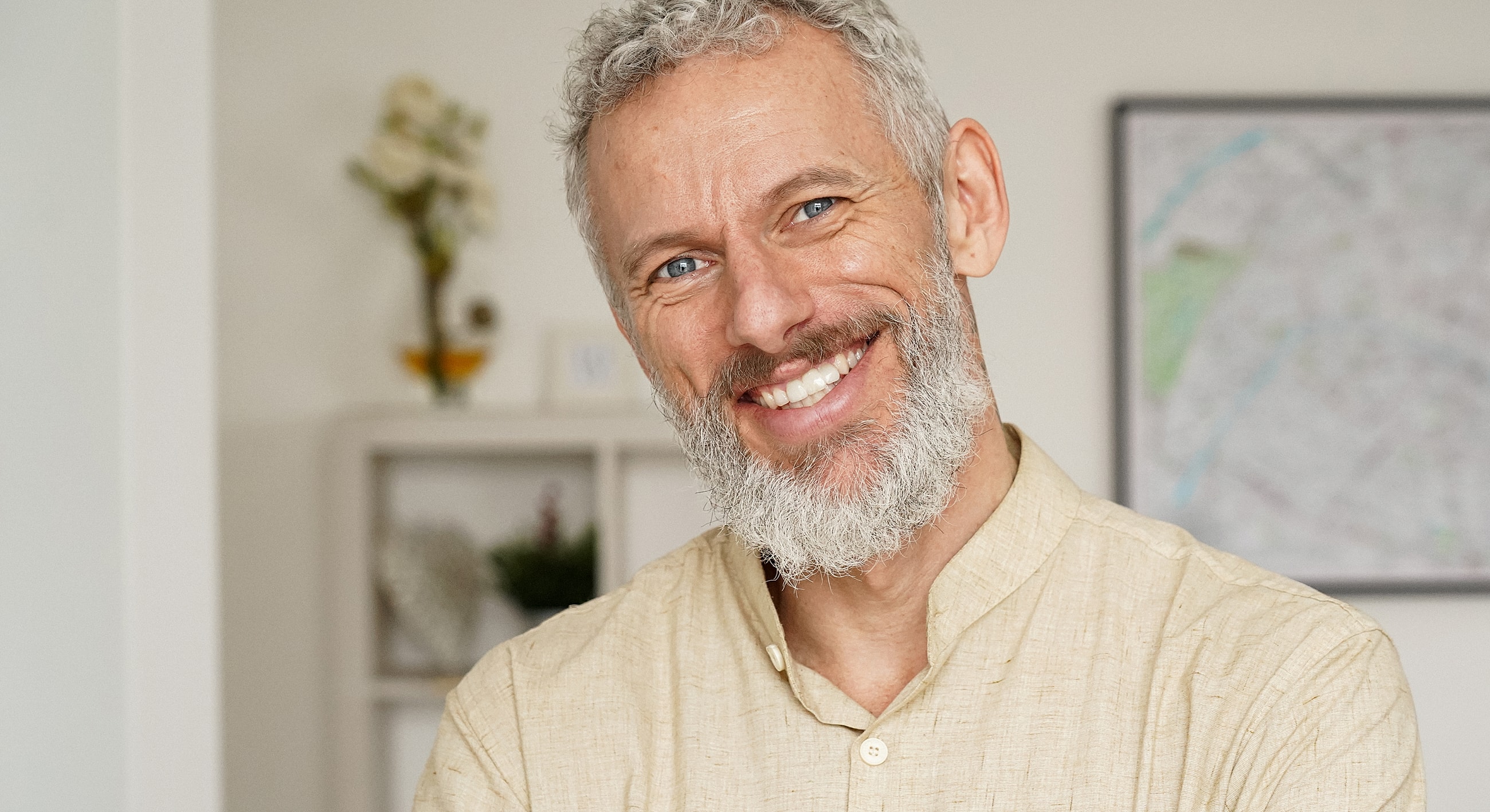 Smiling man with gray beard in casual setting.