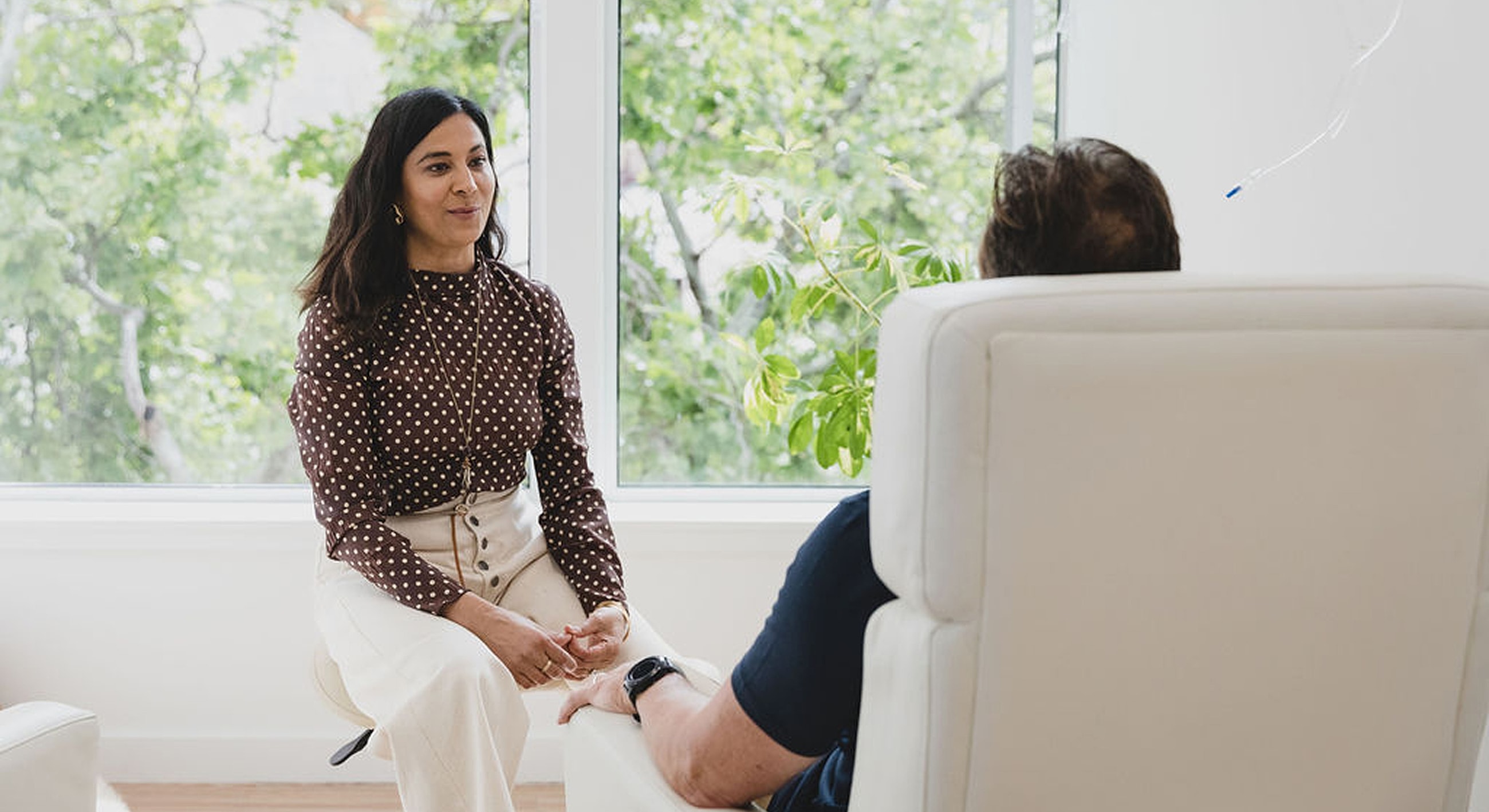 Person sitting and talking in a bright room.